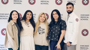 Five people stand in front of a white backdrop with the Chicago Medical School logo on it.