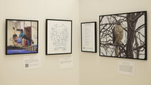 A display of black-framed art, photography, and a printed poem titled "In the Silence"