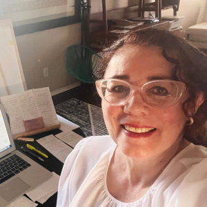 A student taking a selfie in a living room setting with laptop open.