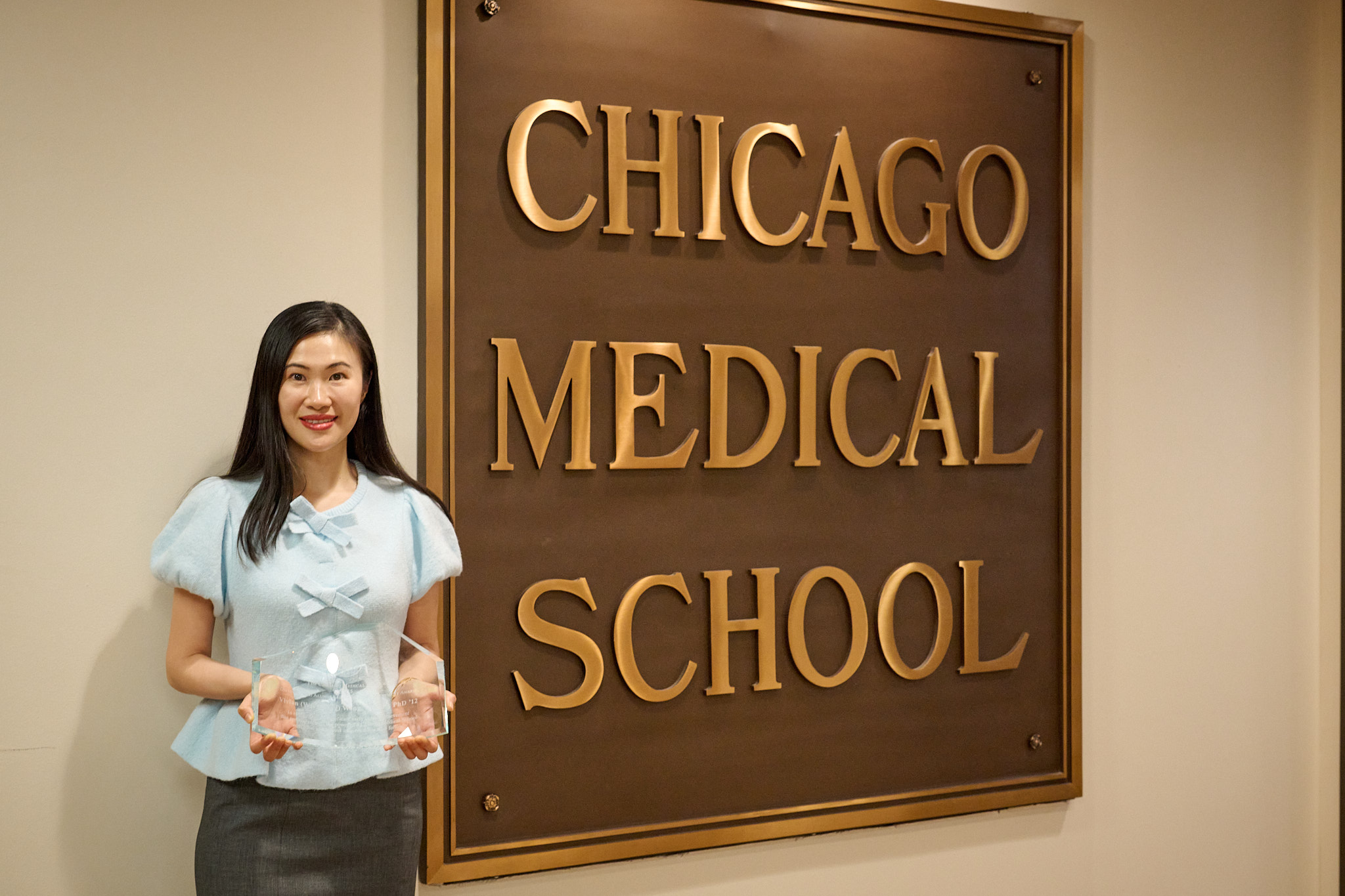 Dr. Vivian Wong stands next to a large metal sign that says "Chicago Medical School"